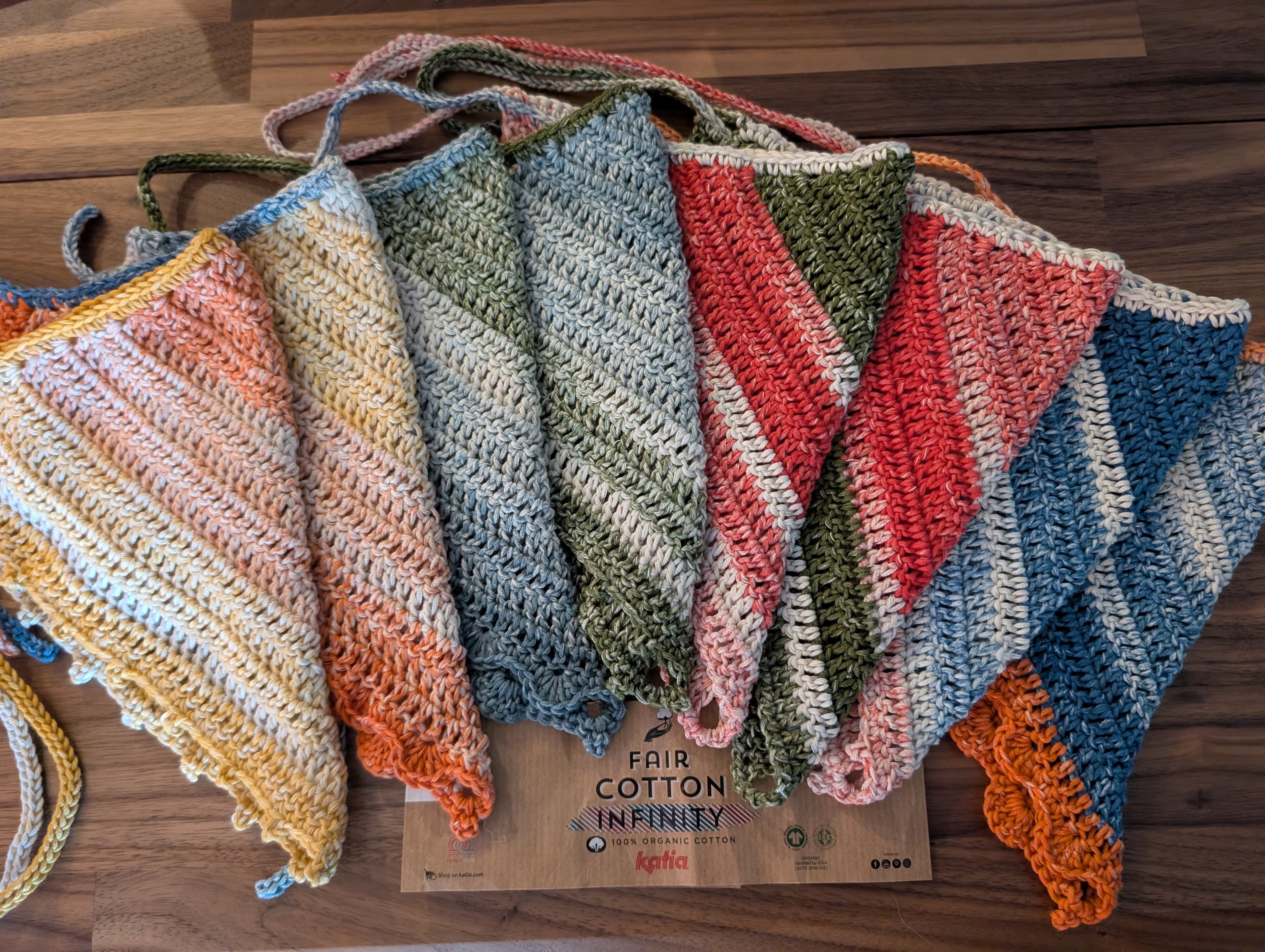 A collection of colorful hand-crocheted bandanas with unique patterns, displayed on a rustic wooden surface