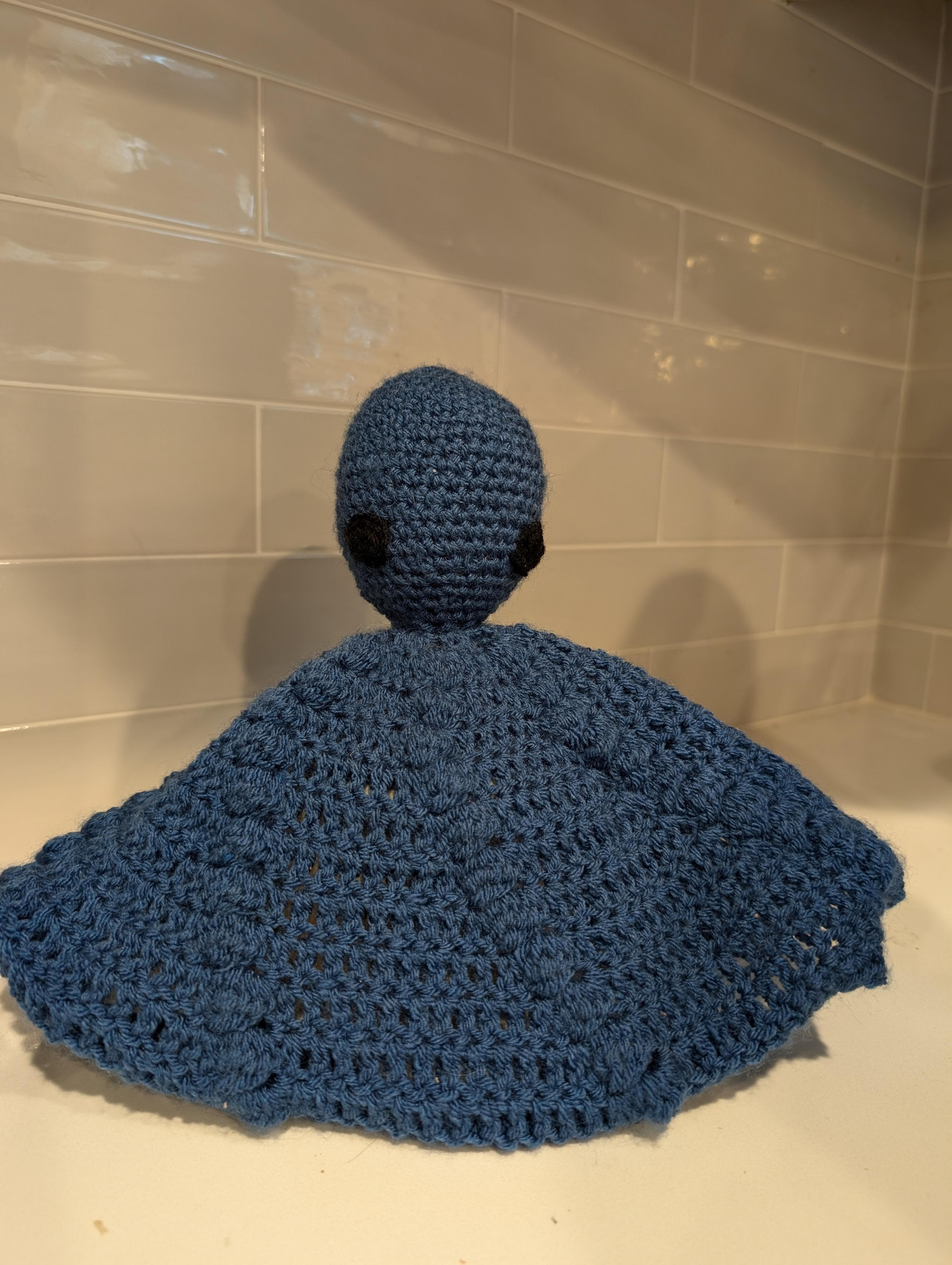 An original hand-crocheted baby blanket featuring a whimsical octopus design, photographed in soft natural light