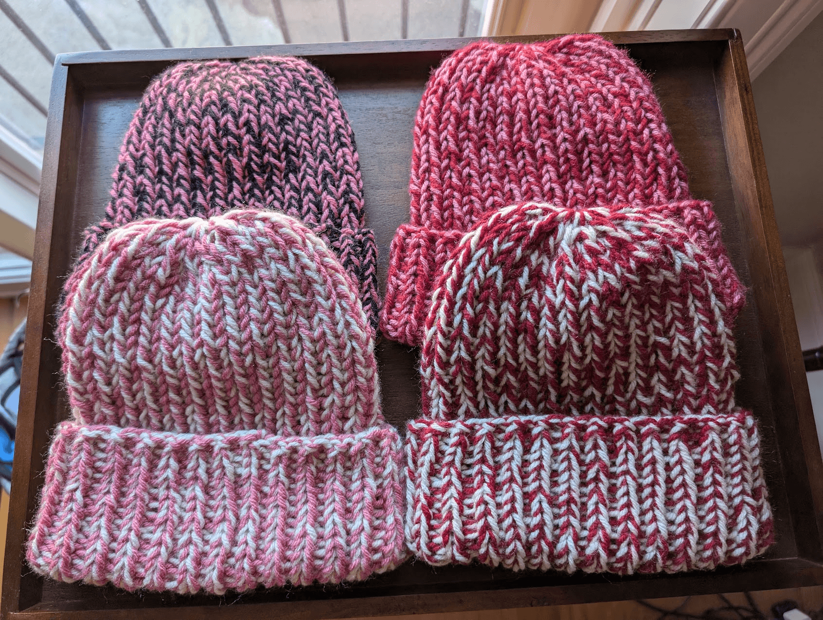 A set of cozy hand-crocheted beanies in red and pink, adorned with heart motifs, perfect for Valentine's Day
